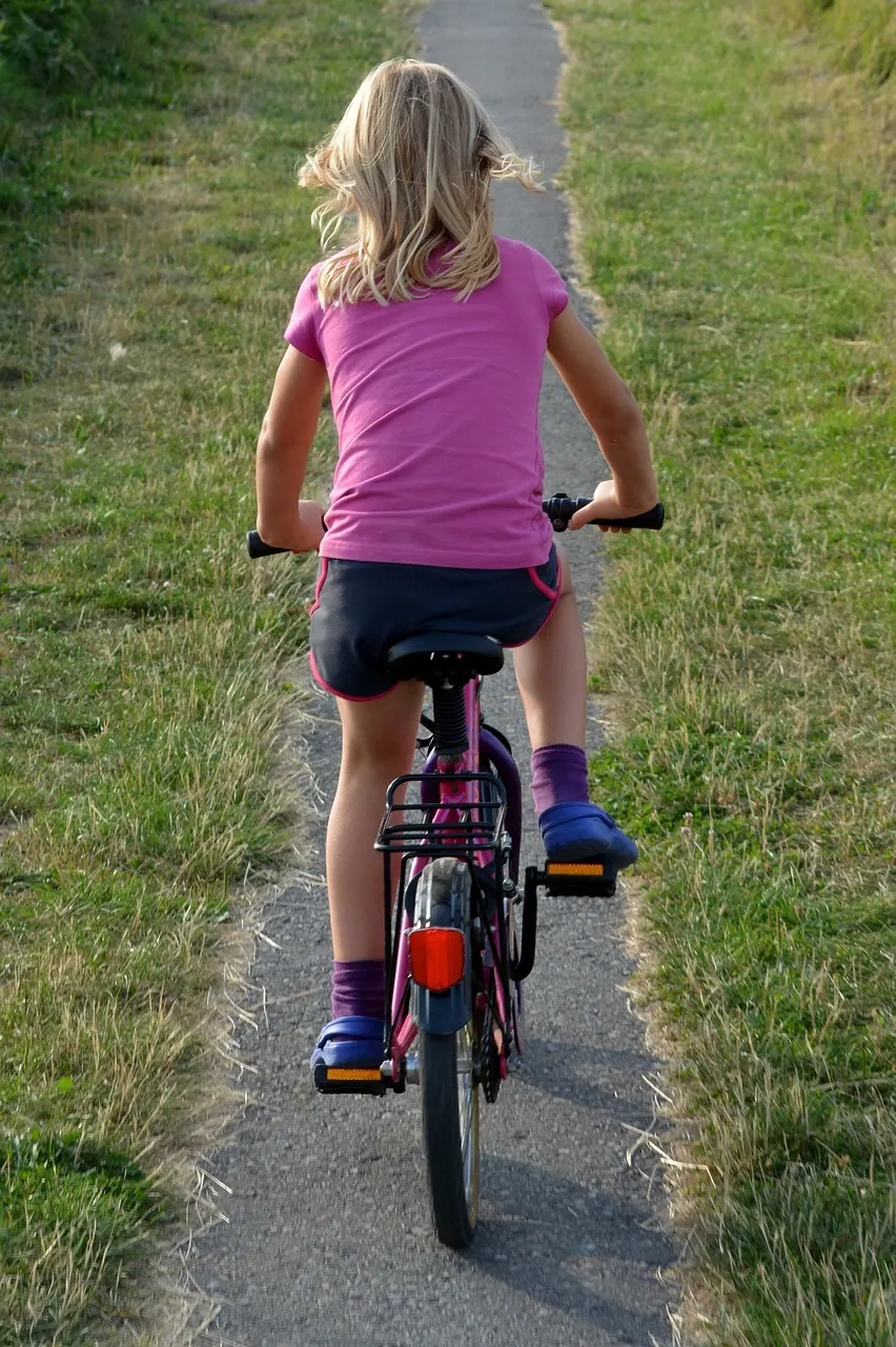 A girl is riding bike by herself.