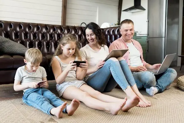 A family is lying on the floor playing with their cell phones.