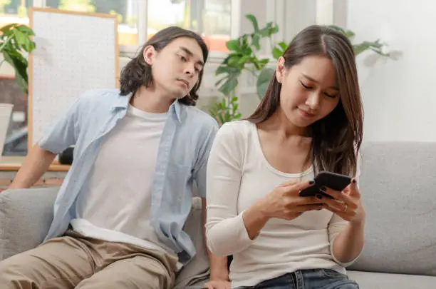 
L’homme regarde le téléphone de sa petite amie derrière son dos